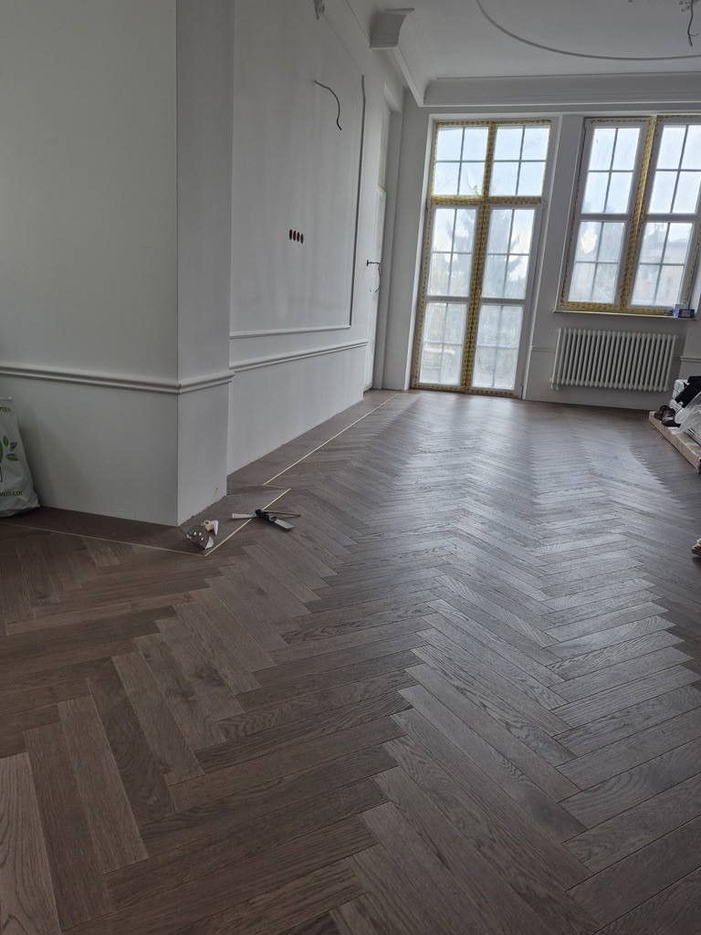 Ciemne deski podłogowe z dębu w jodełkę we wnętrzu ze sztukaterią – realizacja Deska Design