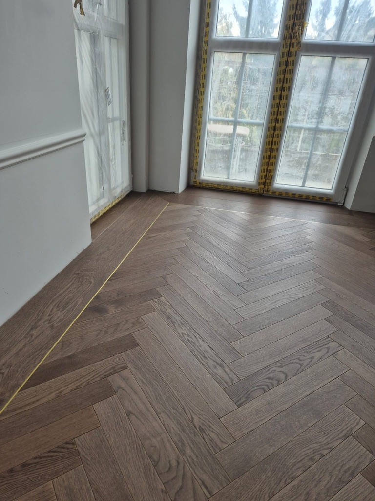 Ciemny dąb w jodełkę z fryzem i mosiężną listwą przy oknach kamienicy – realizacja Deska Design