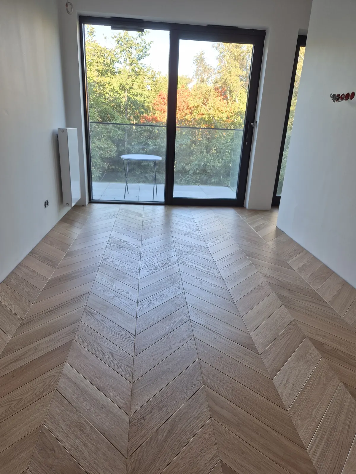 Jodełka francuska z jasnego dębu w pokoju z wyjściem na balkon – realizacja Deska Design
