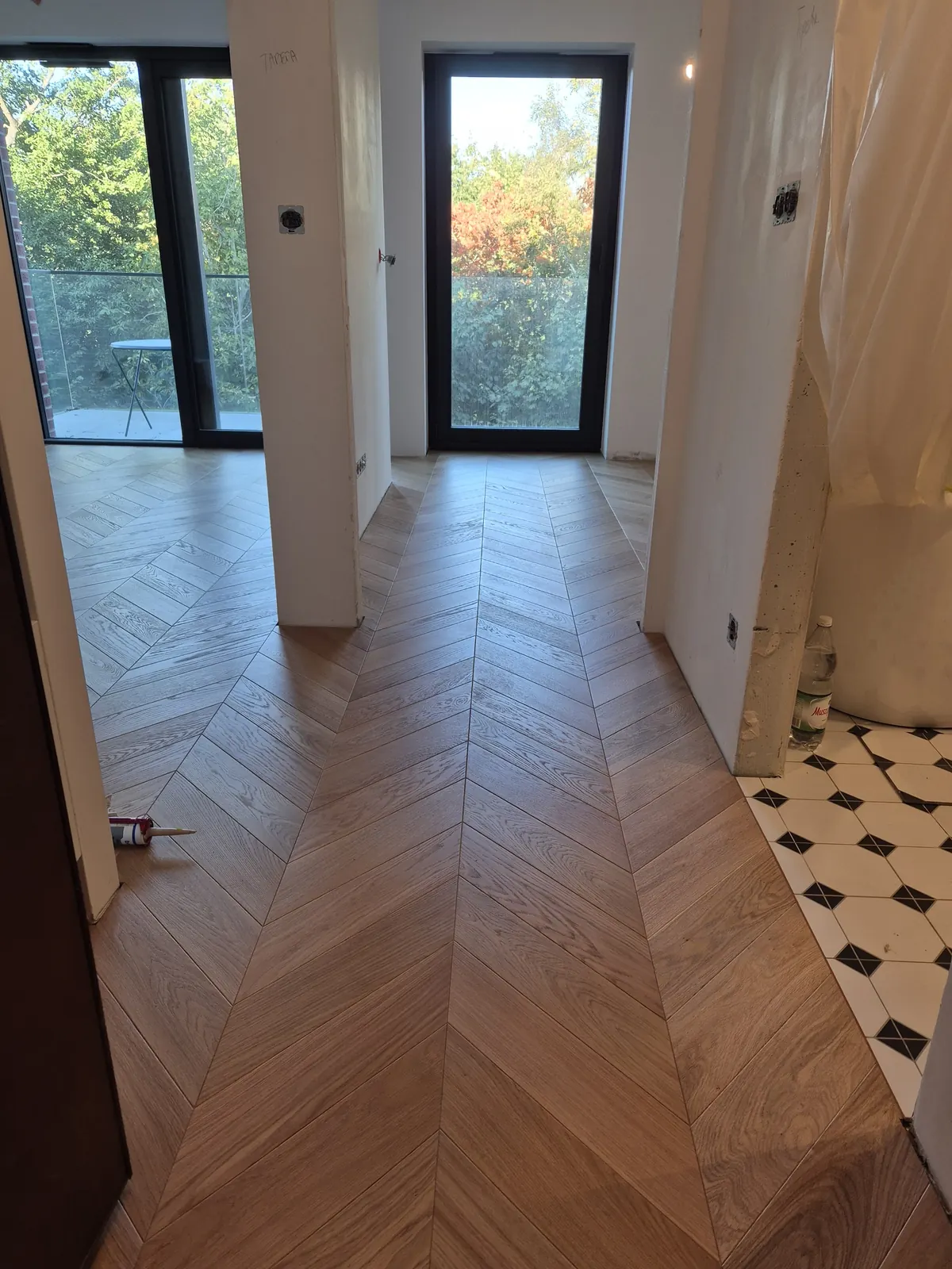 Jodełka francuska w korytarzu przechodząca w czarno-białe płytki łazienki – realizacja Deska Design